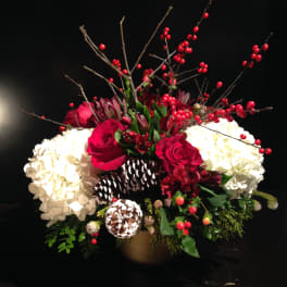 Red roses and white hydrangeas in a gold vase with berry branches