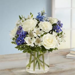 White and blue bouquet in a clear glass vase
