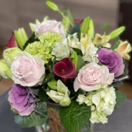 Mixed bouquet with pink roses, lilies, hydrangea, and a burgundy calla lily in a glass vase