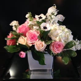 Pink and white roses with white blooms in a square vase