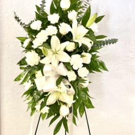 White floral standing spray with lilies and carnations on an easel
