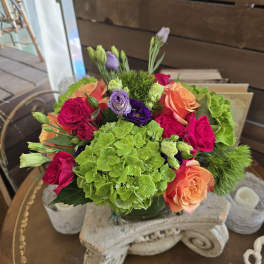 Bouquet of pink, orange, purple, and green flowers in a glass vase