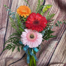 Gerbera daisy bouquet in a glass vase with a blue ribbon
