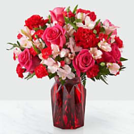 Pink and red mixed flower bouquet in a red glass vase