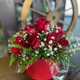 Red roses arranged in a red box with white baby's breath