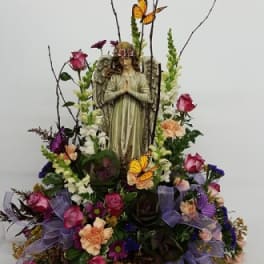 Floral arrangement with an angel figurine, roses, and butterflies