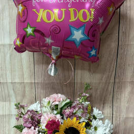 Thank you star balloon with mixed bouquet including sunflower, pink carnations, and white daisies in a glass vase