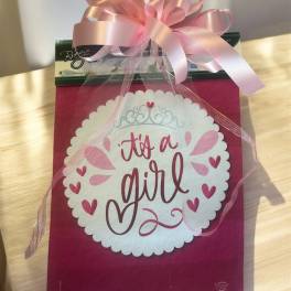 Pink gift bag with a large bow and "it's a girl" message