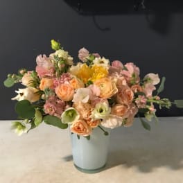 Pastel bouquet of peach, pink, and white flowers in a pale vase