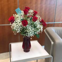 Red roses in a burgundy vase with white baby's breath