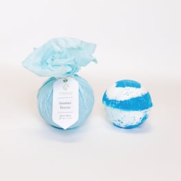Blue bath bomb wrapped in tissue paper beside a striped bath bomb