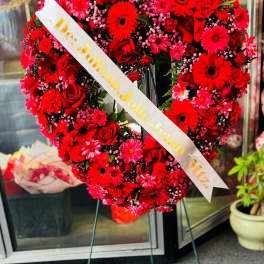 Heart-shaped red flower wreath on an easel with a name ribbon