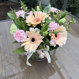 Bouquet of peach gerbera daisies and pink carnations in a glass vase
