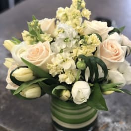 Cream roses and white tulips in a striped glass vase