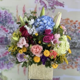 Colorful mixed flower arrangement in a tall square vase
