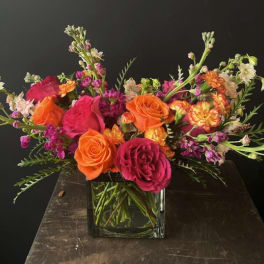 Bright mixed bouquet of orange and pink roses in a glass vase