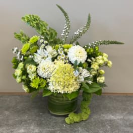 Green and white floral arrangement in a glass vase