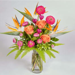 Bouquet of orange roses and pink flowers in a glass vase