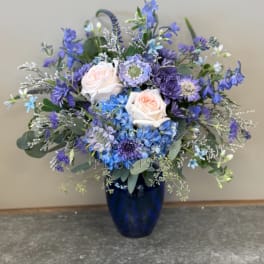 Blue and lavender floral arrangement in a dark blue vase