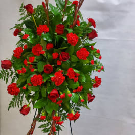 Large red floral standing spray with roses and carnations on a stand