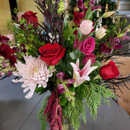 Mixed bouquet with red roses, pink lilies, and a pale chrysanthemum in a glass vase