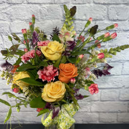 Mixed bouquet of roses, carnations, and snapdragons in a glass vase
