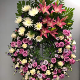Large standing floral wreath with pink lilies, white spider mums, and roses