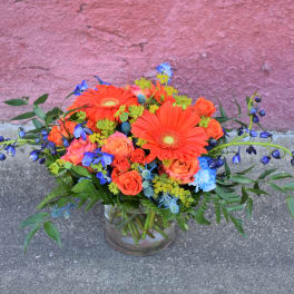 Bright mixed bouquet in a glass vase with orange and blue flowers