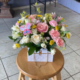 Pink and white flower arrangement in a white gift box