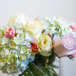 Pastel bouquet of roses and hydrangeas in a clear vase
