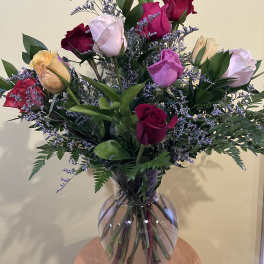 Mixed roses in a clear glass vase with purple filler flowers