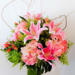 Pink lilies and hydrangeas arranged in a clear glass vase