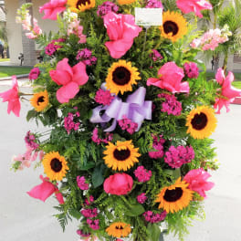 Standing floral spray with pink flowers and sunflowers on an easel