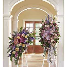 Two large floral standing sprays on white easels in a hallway