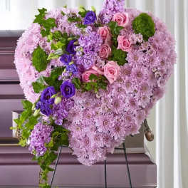Heart-shaped floral arrangement in pink and purple flowers on an easel