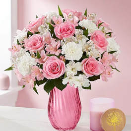Pink roses and white flowers arranged in a pink glass vase