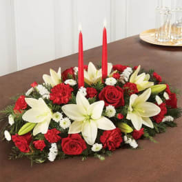 Red and white floral centerpiece with two red candles on a table
