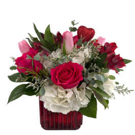 Pink and white flower arrangement in a red vase with a glitter heart pick