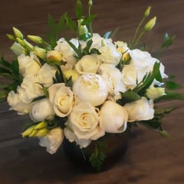 White roses and peonies arranged in a low black vase