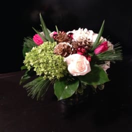 Compact bouquet with pale roses, green hydrangea, and pinecones in a vase