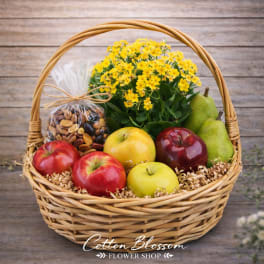 Fruit basket with yellow flowers, apples, pears, and a bag of nuts