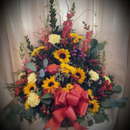 Large mixed flower basket with sunflowers, roses, and a red bow