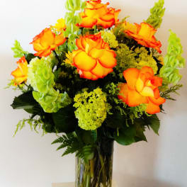 Orange roses with green snapdragons in a glass vase
