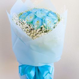 Bouquet of blue roses wrapped in pale blue paper with a ribbon