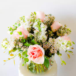 Pink roses and white flowers arranged in a clear glass vase