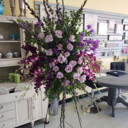 Tall purple floral spray with roses and orchids on a stand