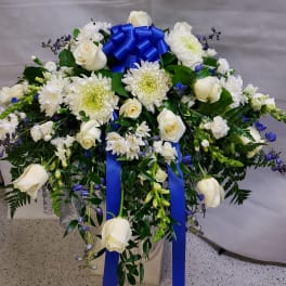 White roses and chrysanthemums in a large arrangement with a blue ribbon bow