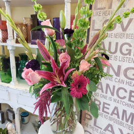 Pink lilies, roses, and gerbera daisies in a clear glass vase