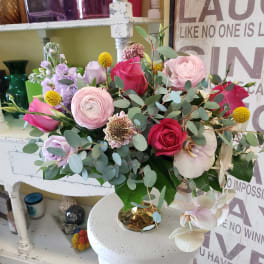 Mixed bouquet of pink and lavender roses with eucalyptus in a gold vase