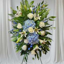 Standing floral spray with white roses, lilies, and blue hydrangeas